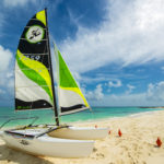 sailboat perched on sand at edge of water that is turquoise green