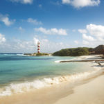 Beach at Hyatt Ziva Cancun with wave washing up on sand and lighthouse in background